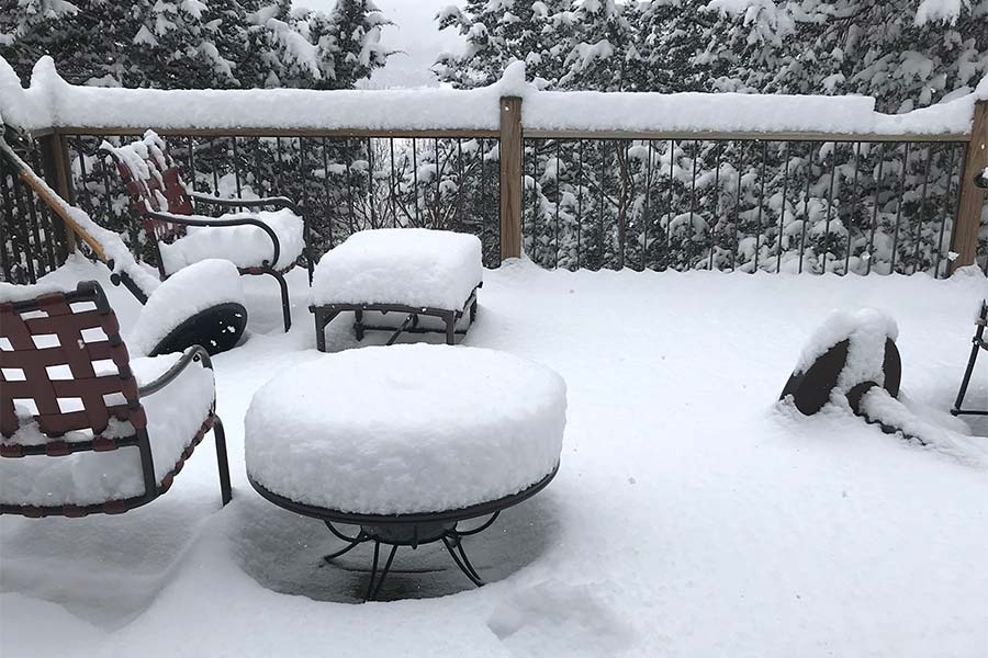 Photo of snow covered deck with outdoor furniture